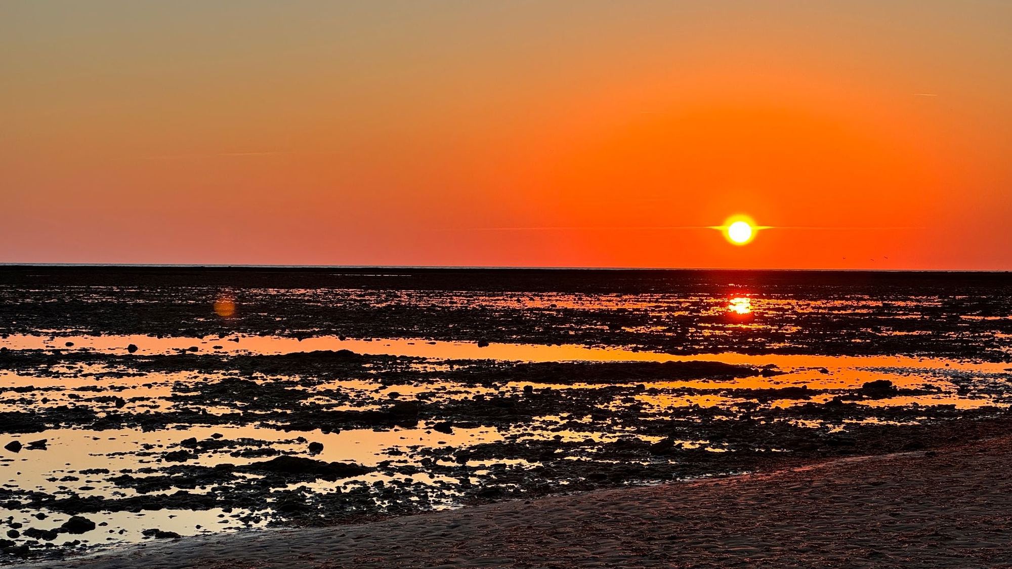 Los corrales al atardecer con el cielo rojo reflejado en el agua