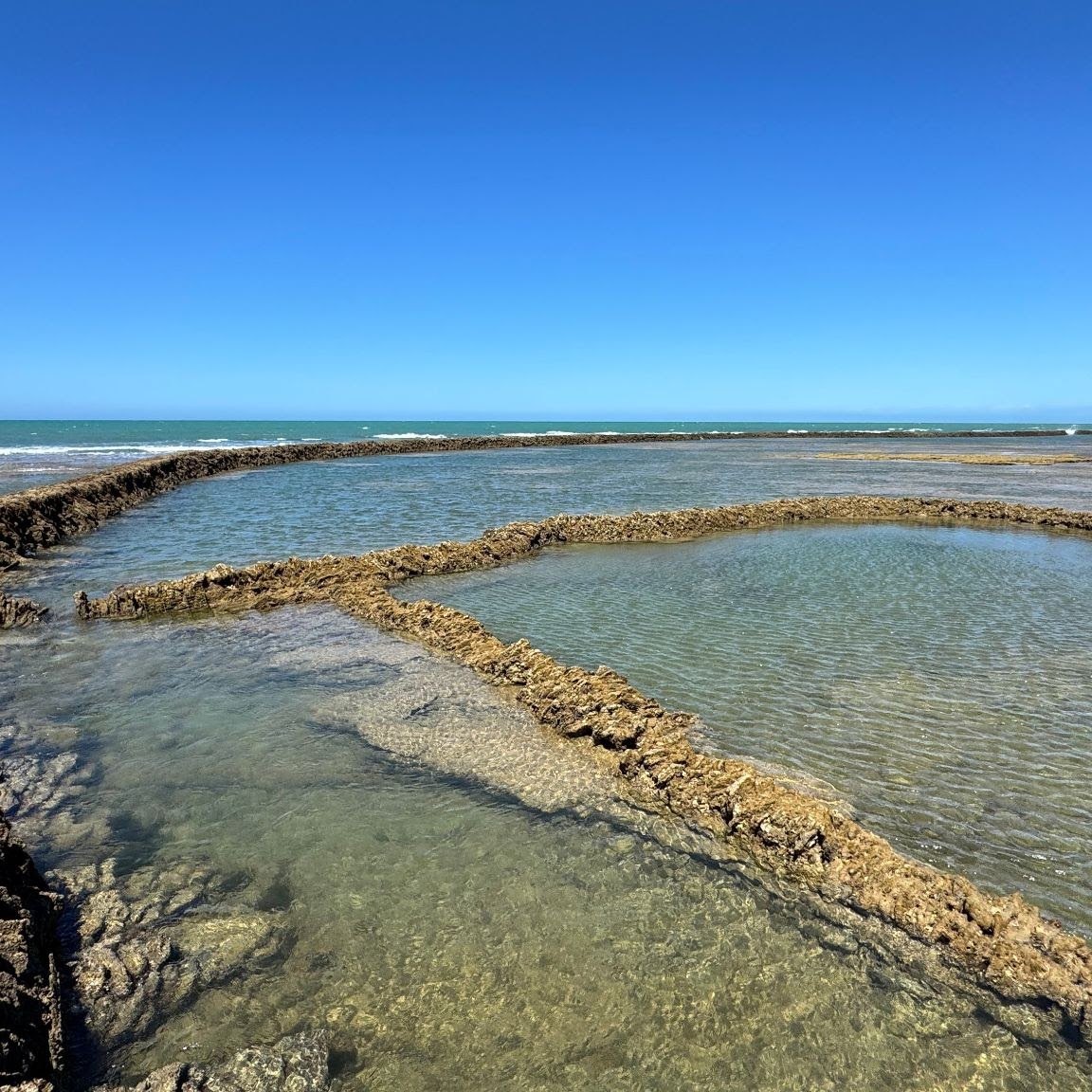 Muros de los corrales y pozas de agua clara con la marea baja